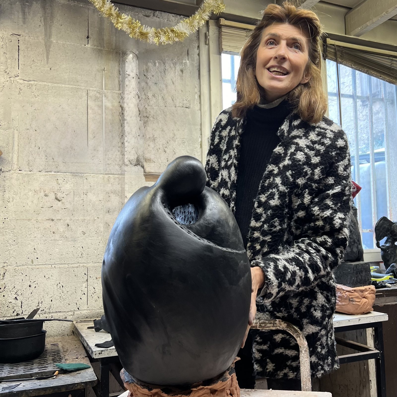 Agnès L-D Steeg souriante à l'atelier, près d'une sculpture
